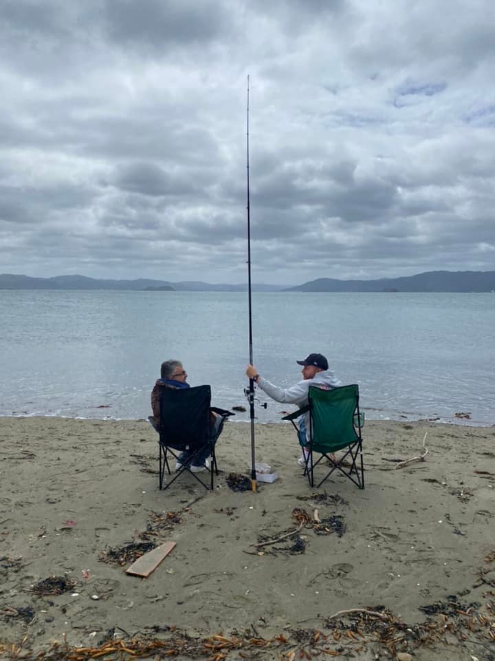 Niko (left) and Harry (right) on a beach shorline, Harry is holding a long line fishing rod