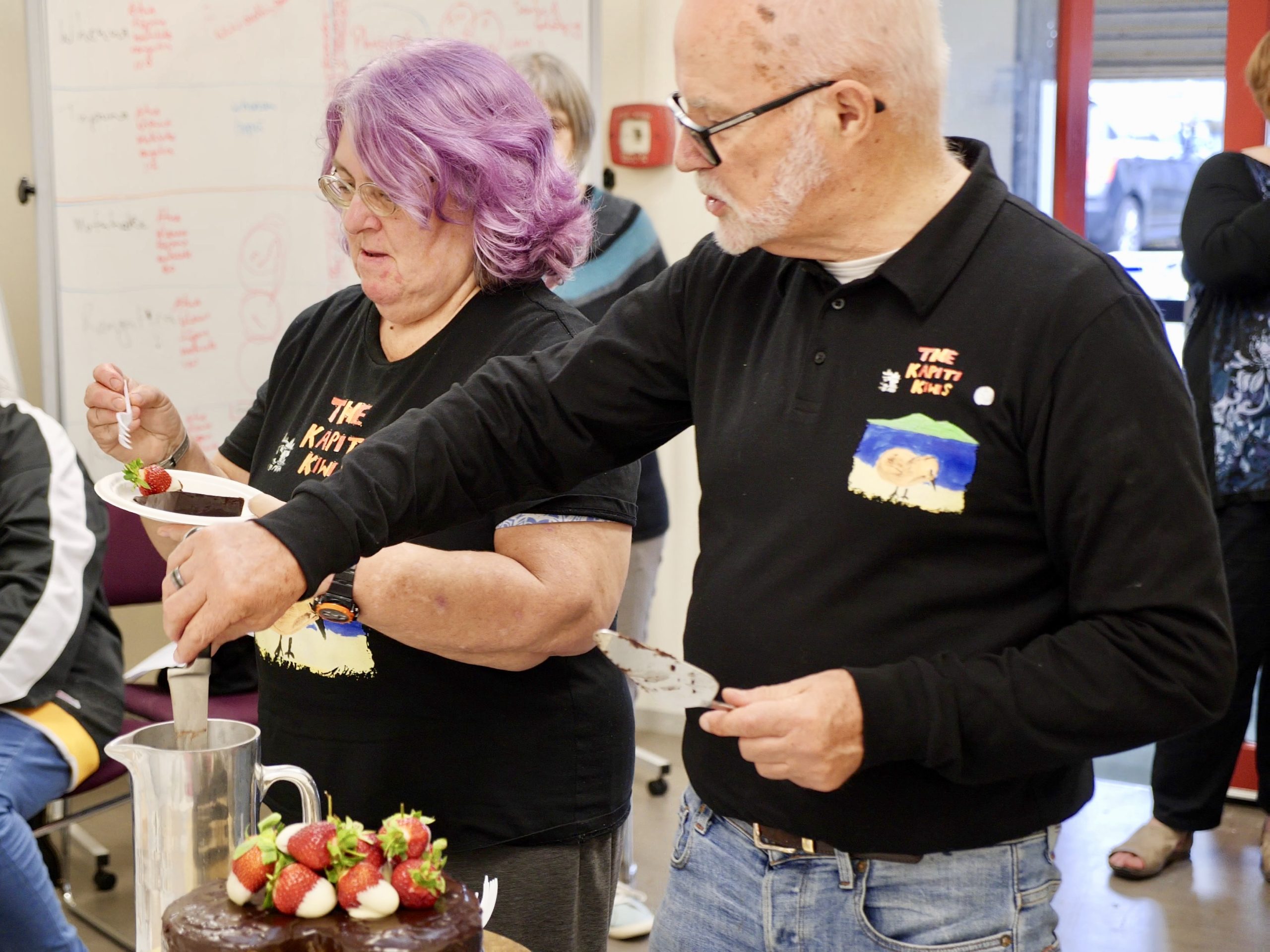 Kapiti Kiwi’s network group Brian (right) serving cake to the Kāpiti Kiwis network group
