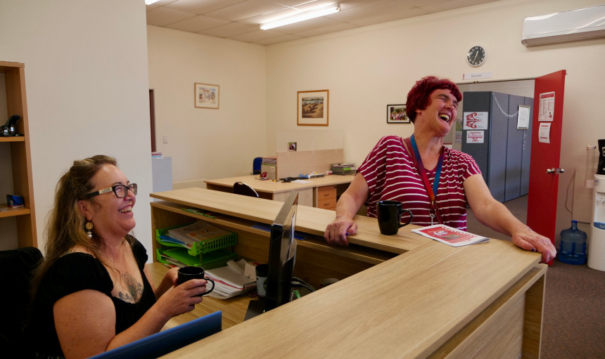 cardThree Sara (left) sitting behind the reception desk with Trish (right) leaning on the outside laughing