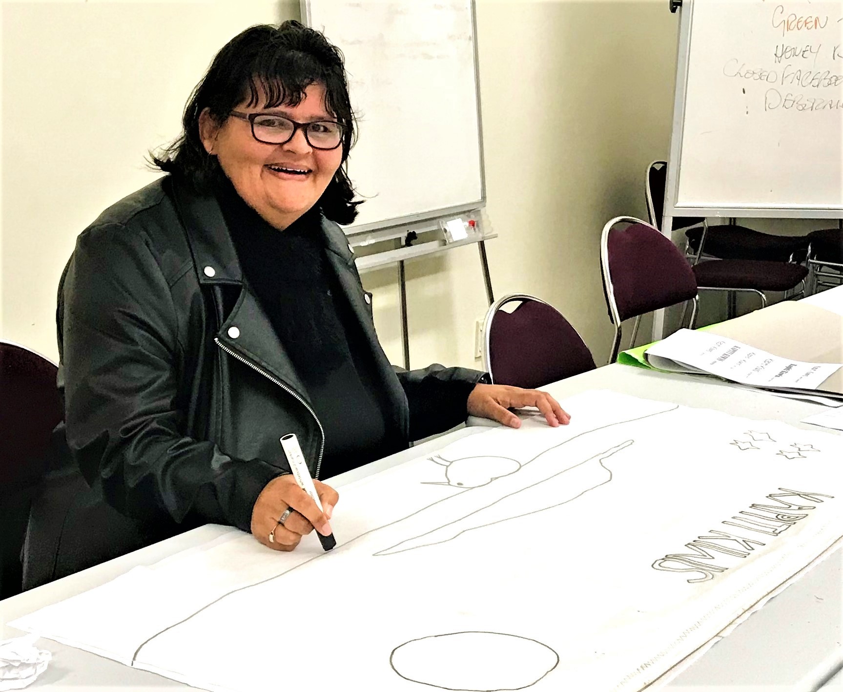 Jane, from the Kāpiti Kiwis network group, drawing up a design for their logo 